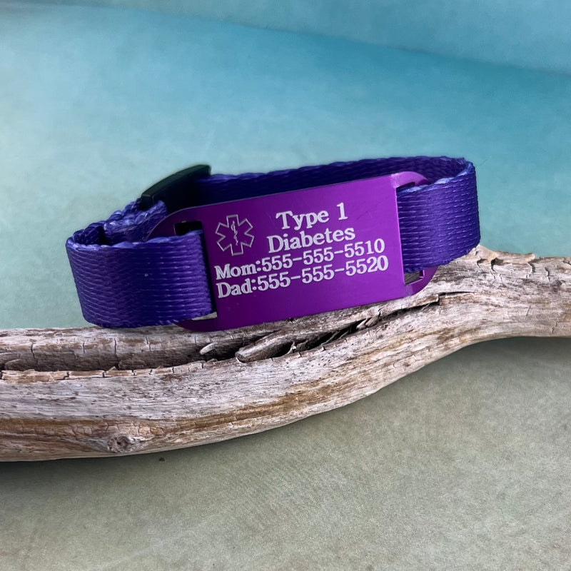 Purple Type 1 Diabetes kids medical alert bracelet displayed on a piece of wood.