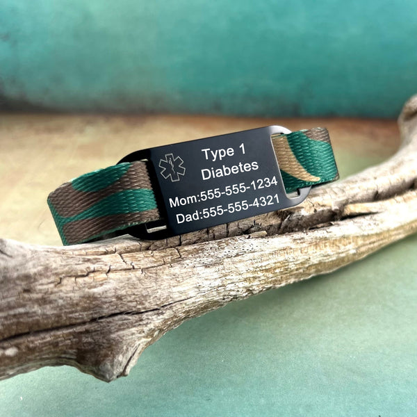 Camouflage print nylon kids Type 1 diabetes medical alert bracelet displayed on a piece of wood.