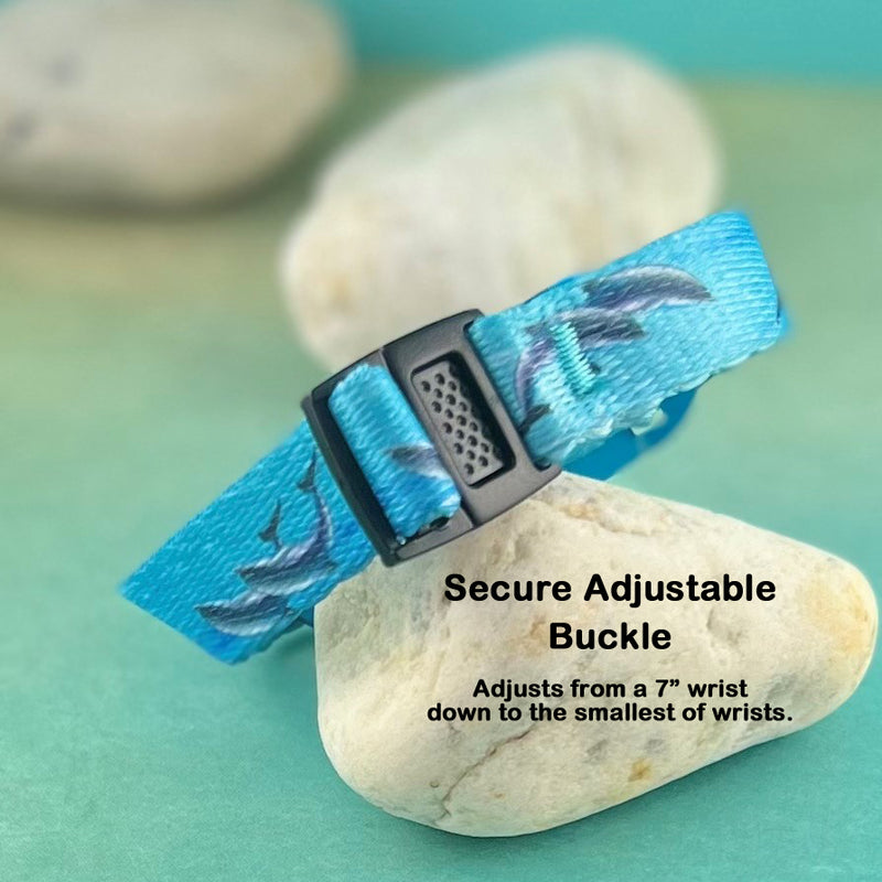 Center push black adjustable buckle on a dolphin print blue band displayed on a rock.