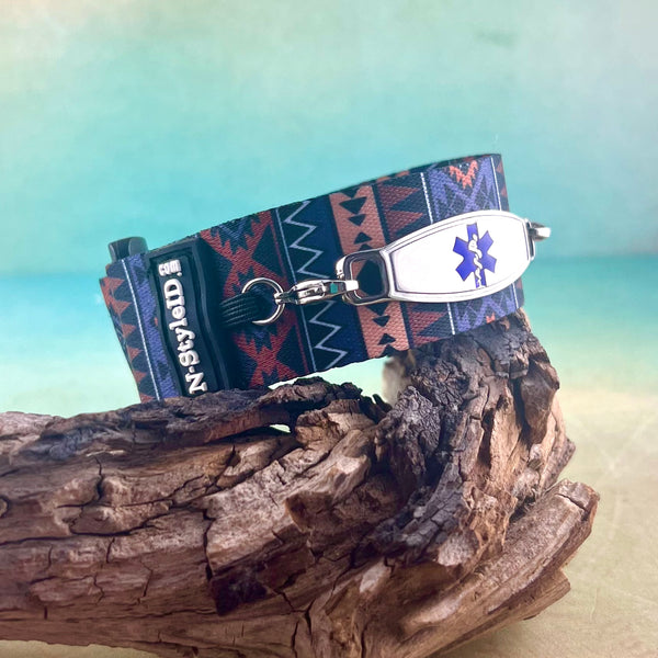 Velcro medical alert bracelet in an Aztec print displayed on a piece of wood. ￼