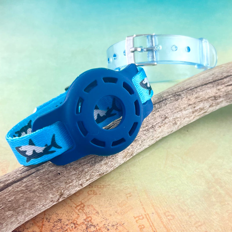Blue Airtag bracelet with shark print with light blue silicone band displayed on a piece of wood.