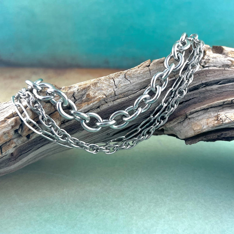 3 stainless steel chains displayed on a piece of wood.