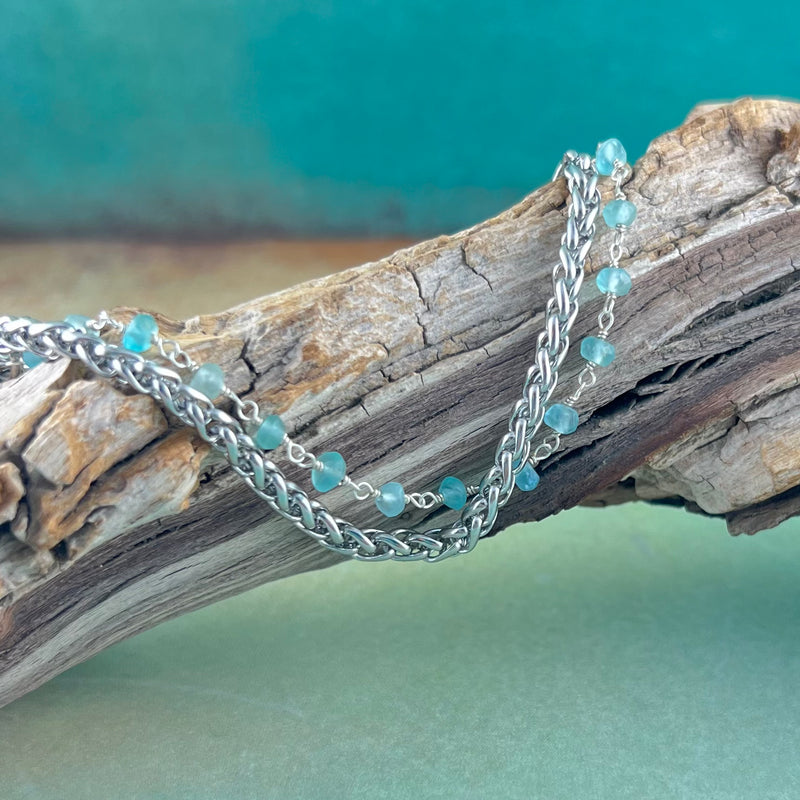Stainless steel medical ID bracelet with a silver wire wrapped chain with apatite stones in blue displayed on a piece of wood..