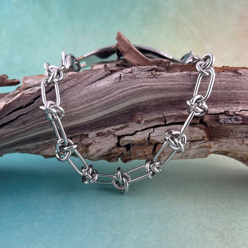 Barbed wire stainless steel replacement medical alert bracelet displayed on a piece of wood.