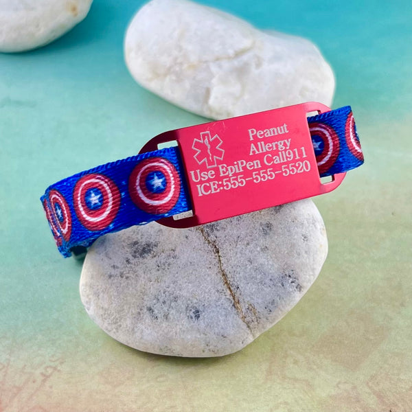 Blue nylon with red bullseye and star print kids medical alert bracelet propped up on a rock.