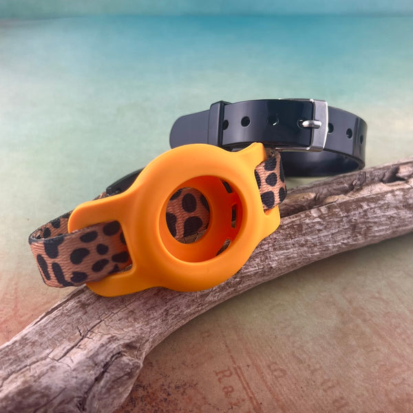 Cheetah print AirTag bracelet with orange AirTag holder and black silicone band displayed on a piece of wood.