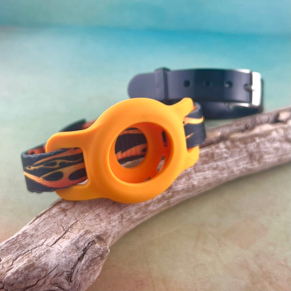 Fire print AirTag bracelet with orange AirTag holder and black silicone bracelet displayed on a piece of wood.