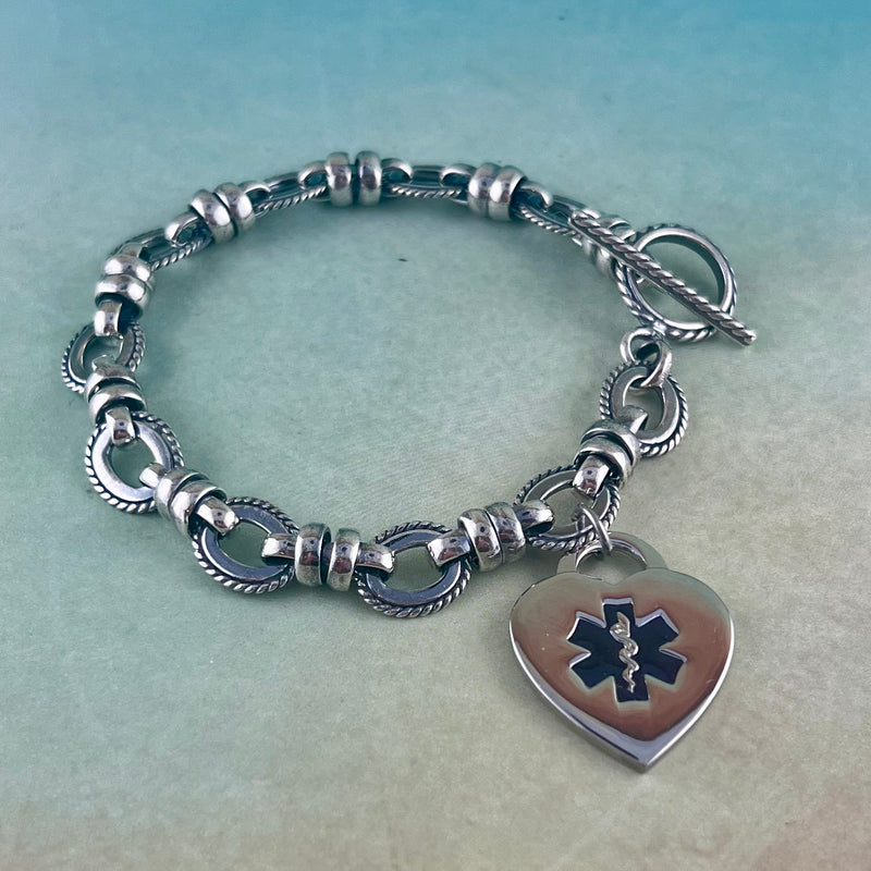 Silver medical alert charm bracelet with black star of life heart shaped medical charm.