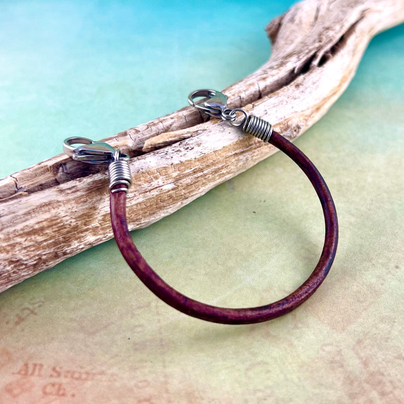 Brown leather replacement medical alert bracelet displayed on a piece of wood.