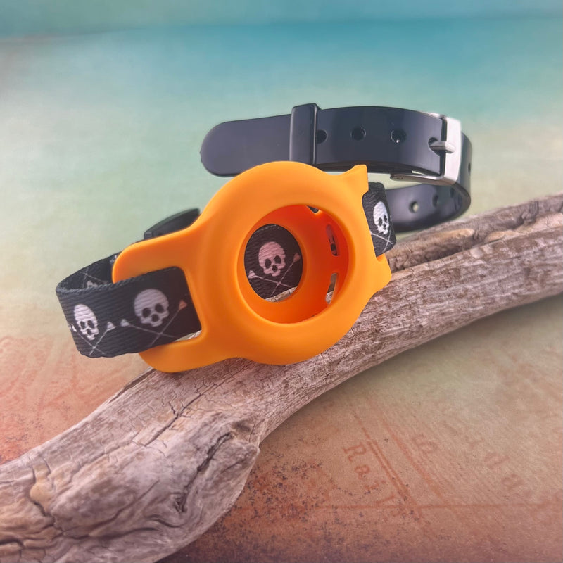 Skull & Crossbones Airtag bracelet with orange airtag holder and black silicone bracelet displayed on a piece of wood.