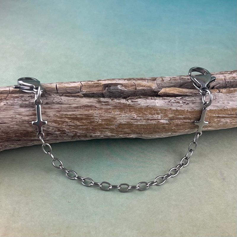 Stainless steel replacement medical alert bracelet with 2 sideways crosses displayed on a piece of wood.