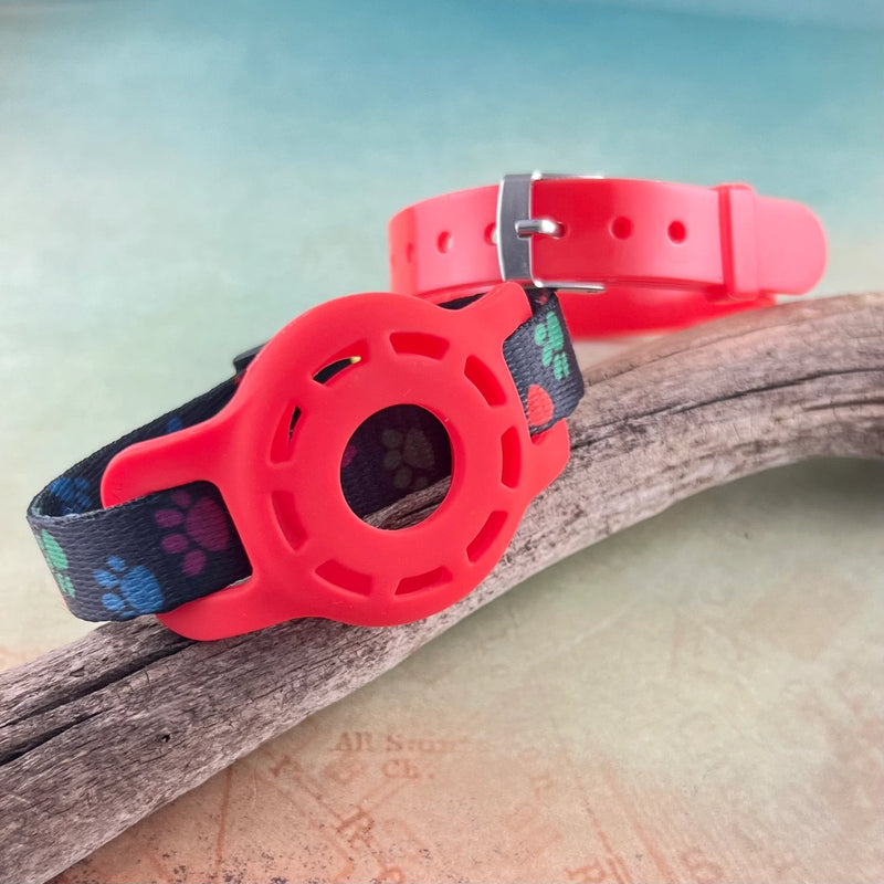 Paw print kids AirTag bracelet with red AirTag holder and red silicone band displayed on a piece of wood.