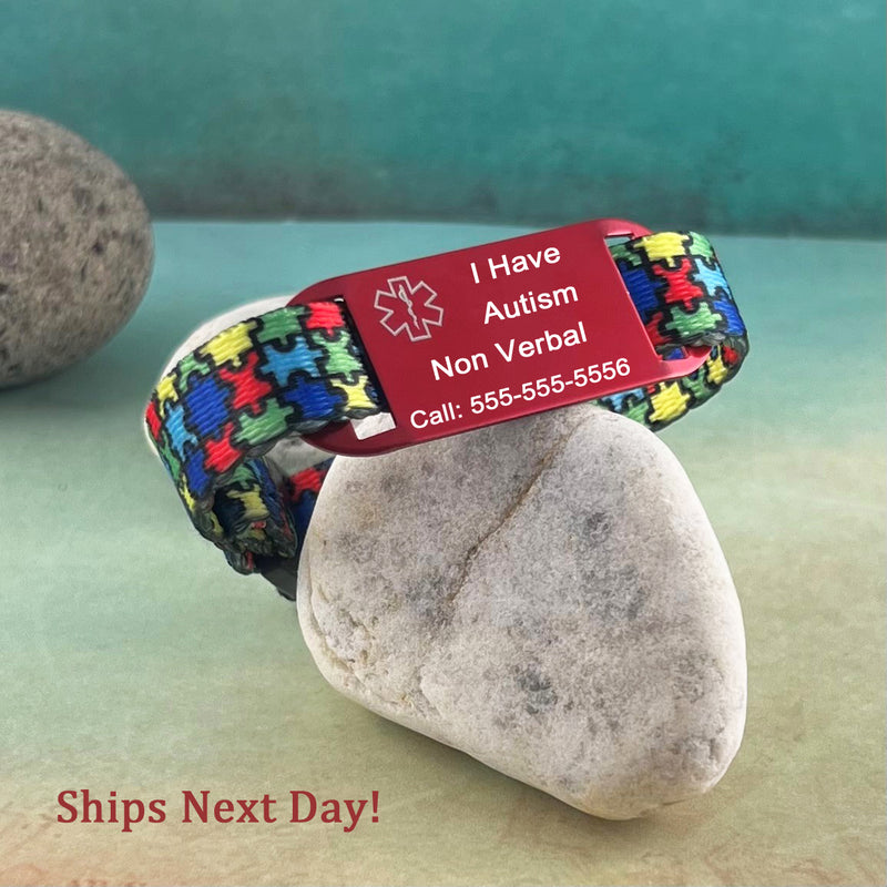 Puzzle print medical alert bracelet with personalized medical ID tag displayed on a rock.