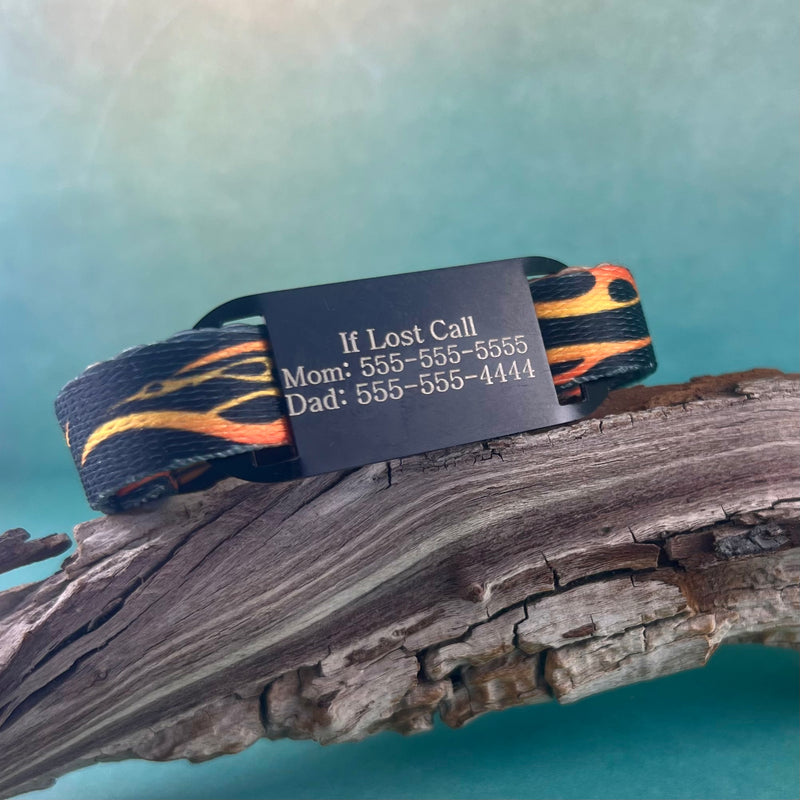 Flame print kids ID bracelet with personalized engraved ID tag displayed on a piece of wood.