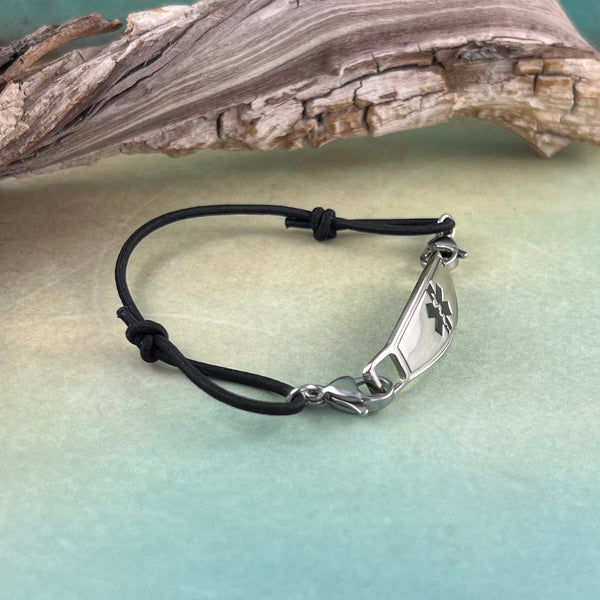 Black thin cord adjustable medical alert bracelet displayed in front of a piece of wood.