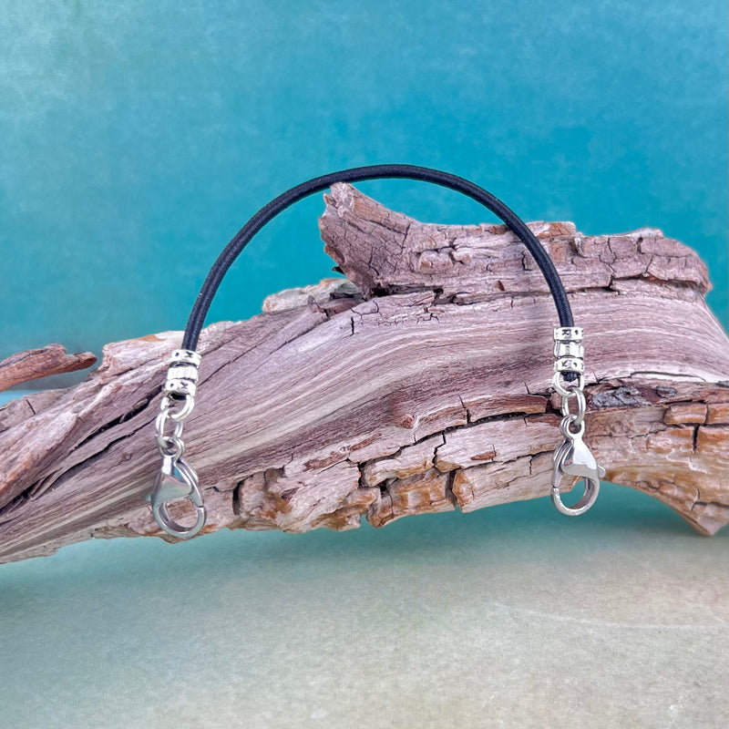 Black stretch cord replacement medical alert bracelet displayed on a log.