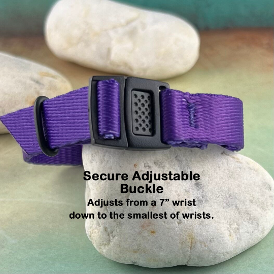 Purple kids medical alert bracelet displayed on a rock.